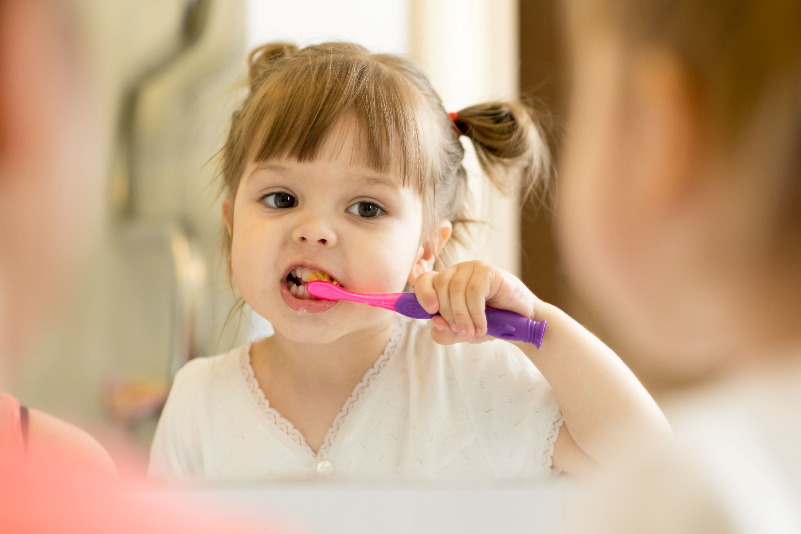 young girl brushing teeth in mirror early dental care little kid dentist