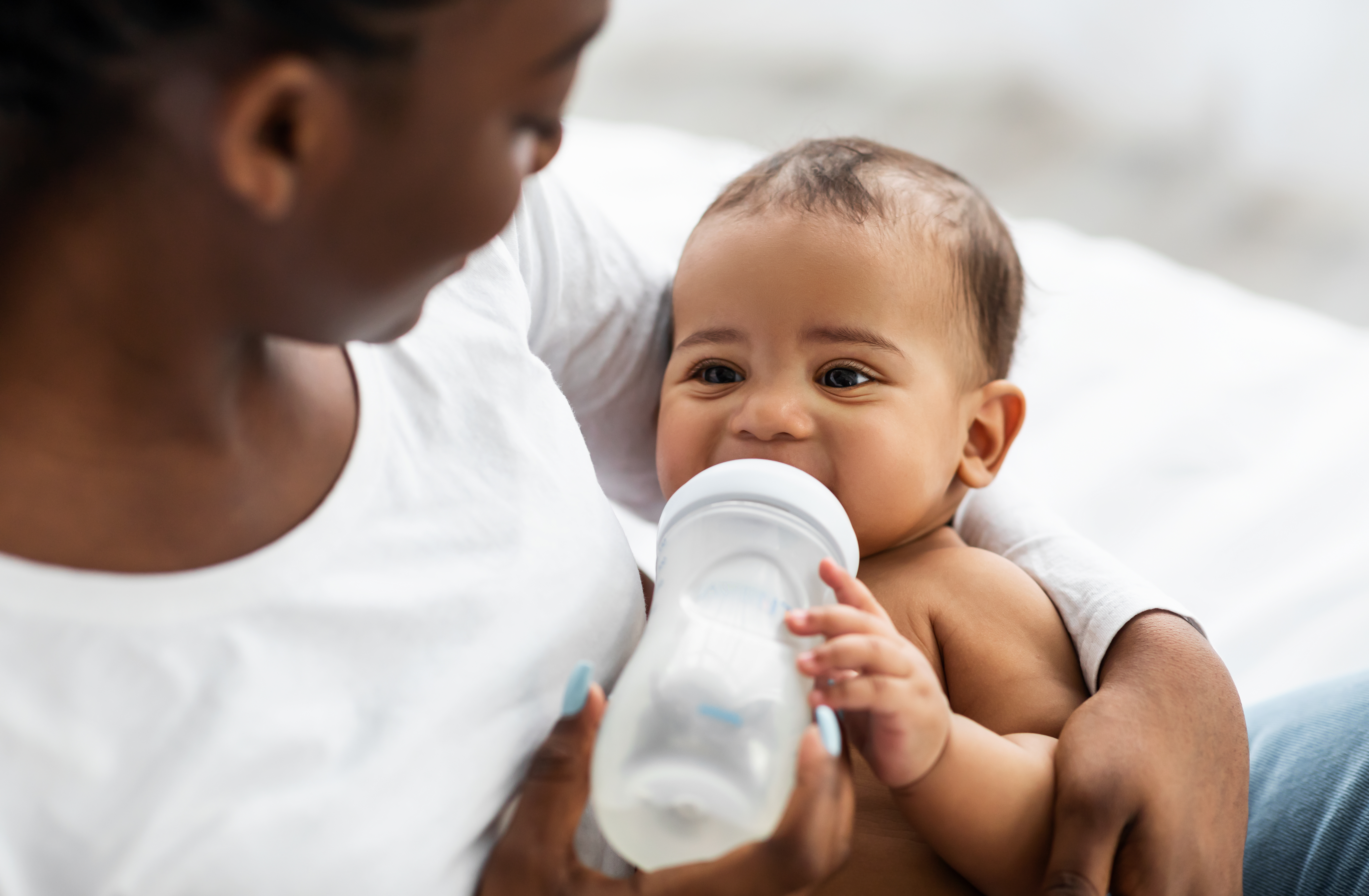 baby drinking bottle in moms arms milk protein allergy article