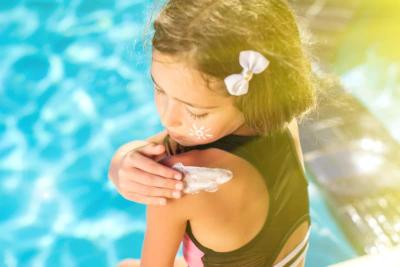 girl applying sunscreen by pool summer tips spring swimming