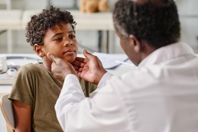African American parent with hands on childs neck checking sore throat sick illness
