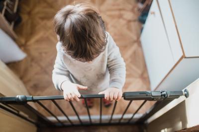 toddler standing at locked baby gate babyproofing home safety