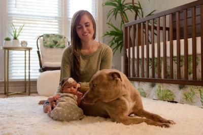 mom with newborn baby and dog in nursery
